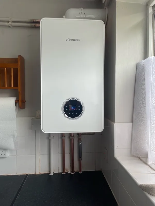 A tankless water heater in a bathroom next to a window.
