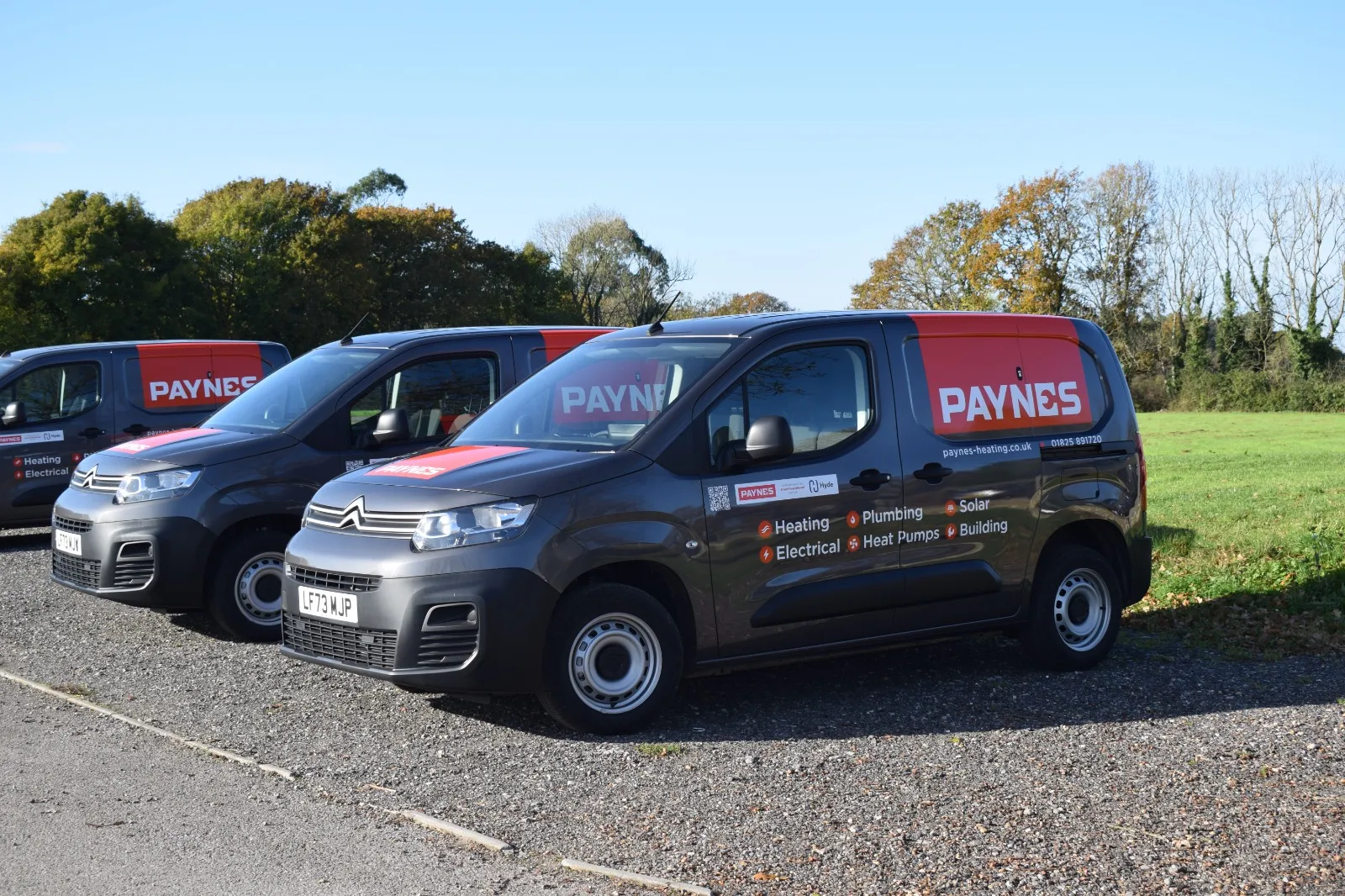 Three vans parked in a row in a parking lot.