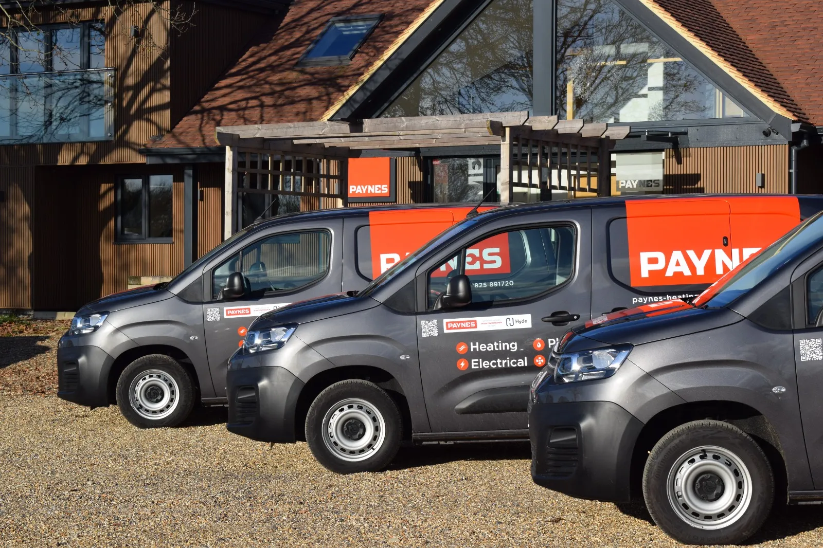 Three small vans parked in front of a building.