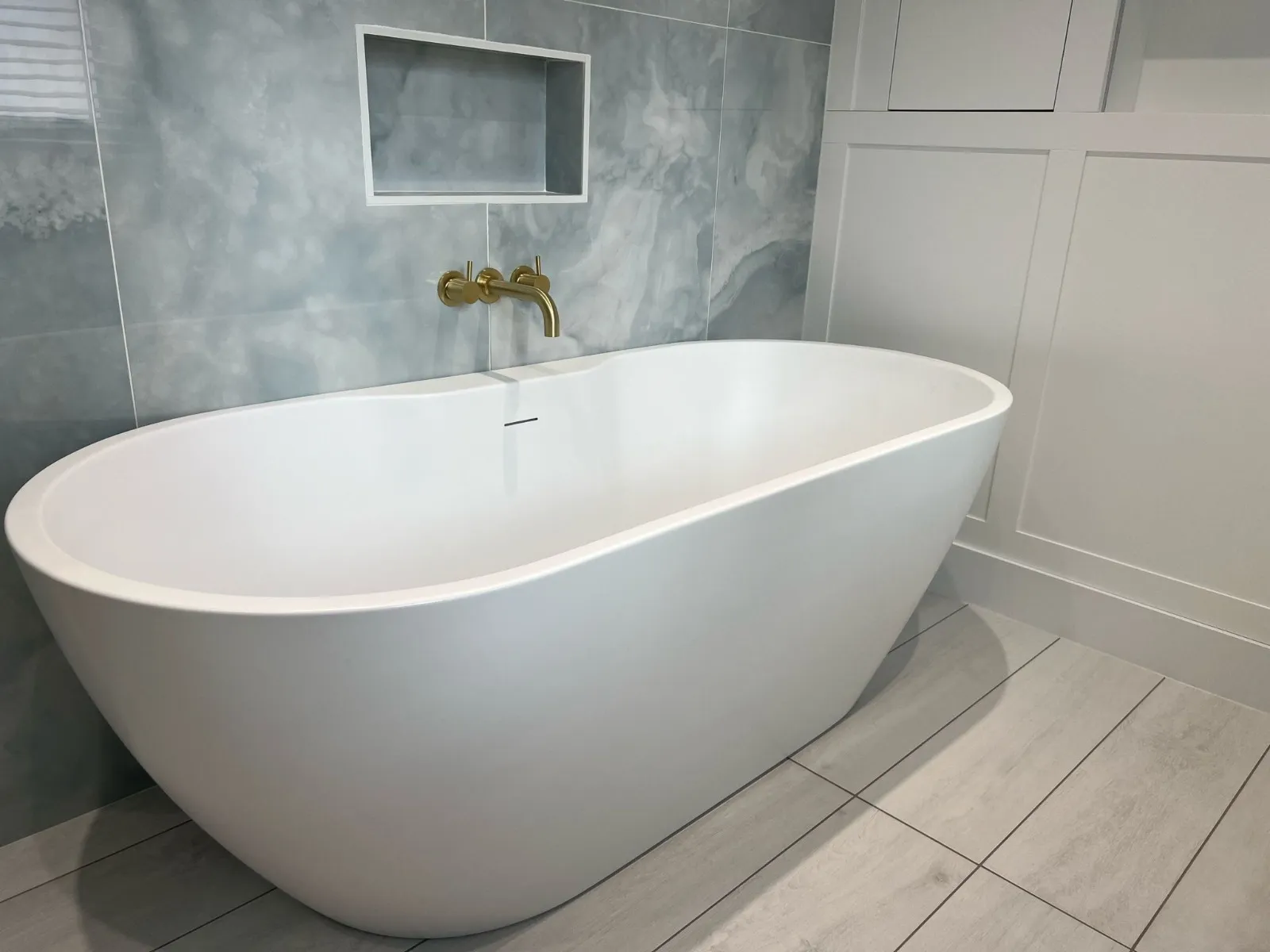 A white bath tub sitting on top of a tiled floor.