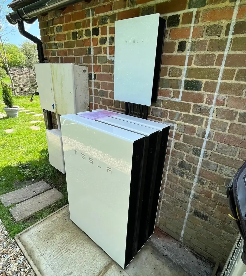 A white refrigerator sitting next to a brick building.