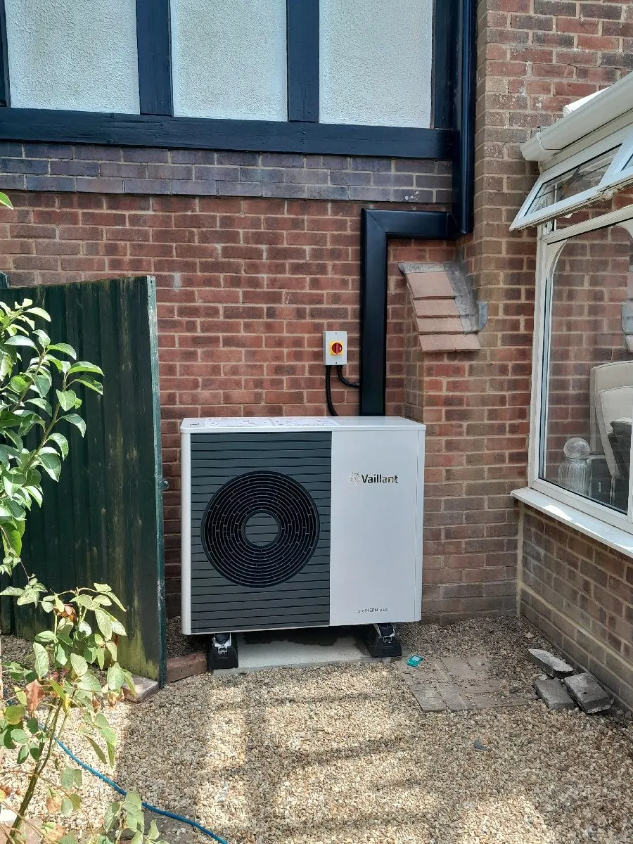 A small air conditioner sitting outside of a brick building.